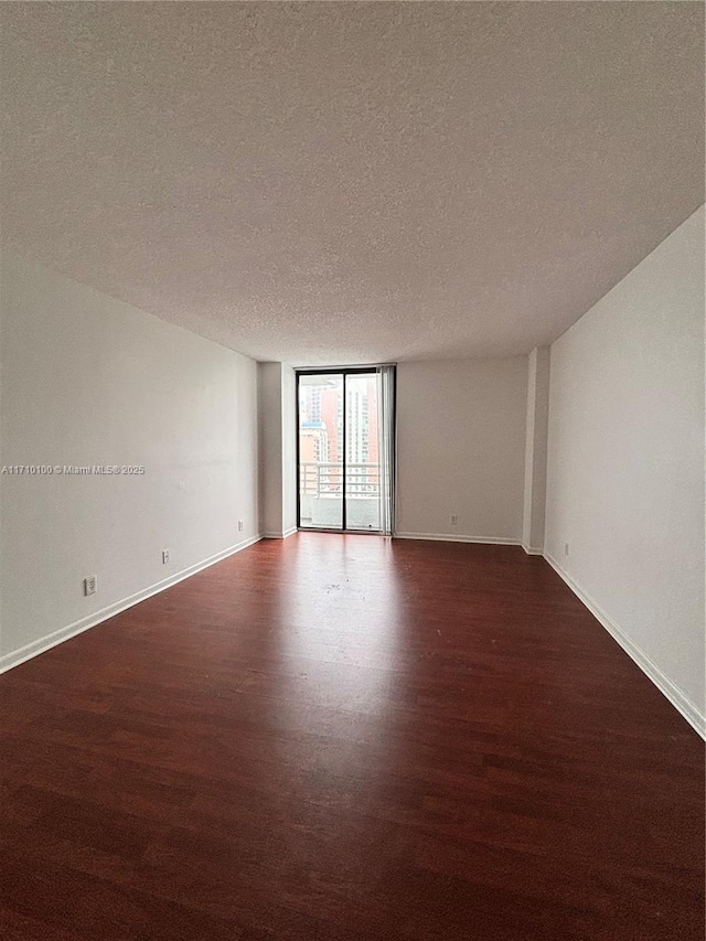 unfurnished room featuring floor to ceiling windows, dark hardwood / wood-style floors, and a textured ceiling