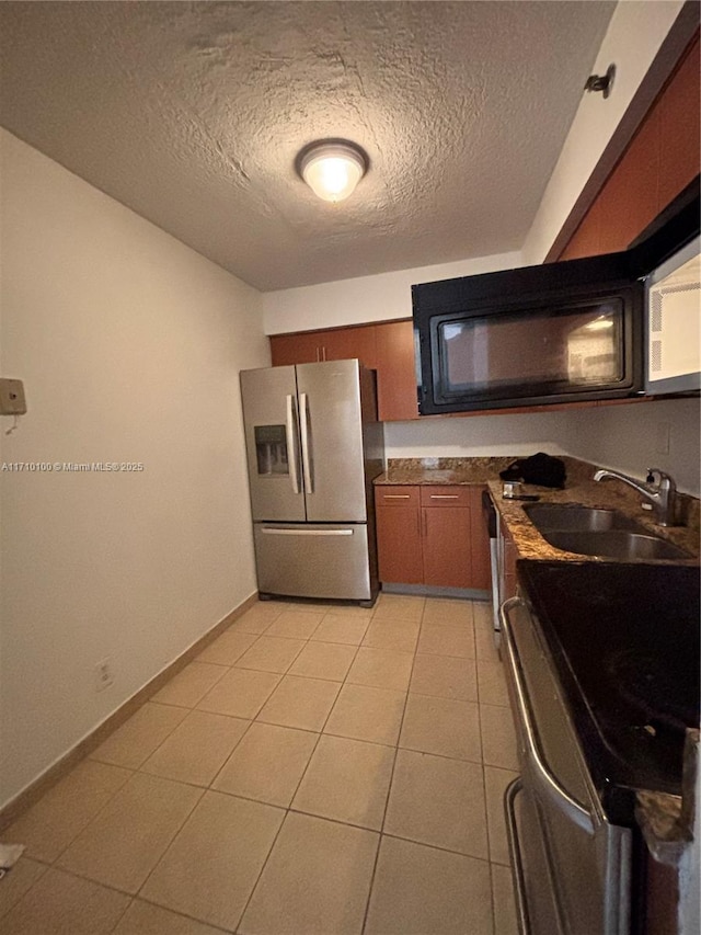 kitchen with sink, light tile patterned flooring, a textured ceiling, and appliances with stainless steel finishes