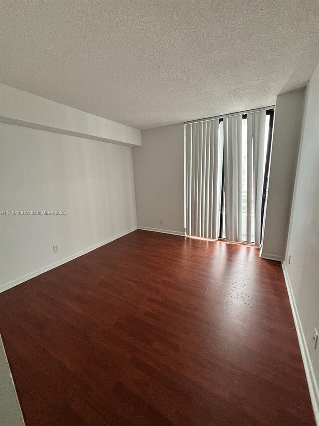 spare room featuring a textured ceiling and dark hardwood / wood-style flooring