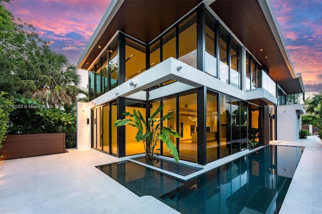 back house at dusk featuring a balcony