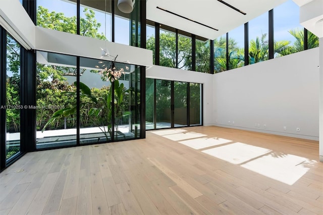 unfurnished living room featuring wood finished floors and a towering ceiling