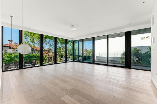 empty room featuring a wall of windows and wood finished floors