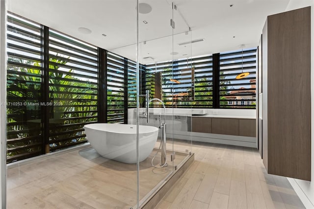 full bathroom with a freestanding tub, visible vents, and wood finished floors