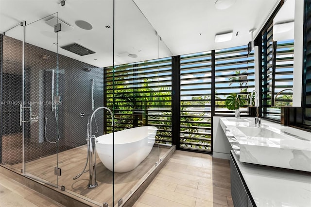 bathroom featuring floor to ceiling windows, double vanity, a stall shower, wood finished floors, and a soaking tub