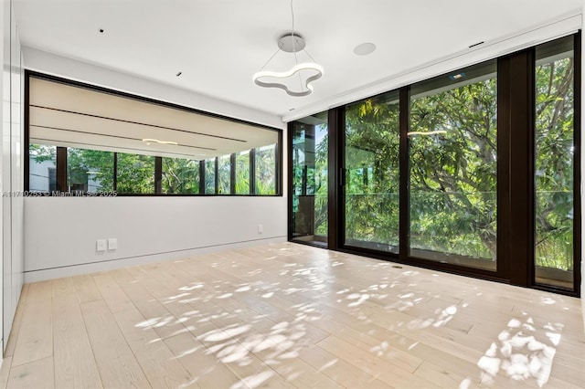 spare room with a chandelier and wood finished floors