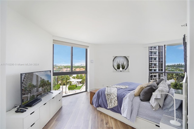 bedroom featuring a wall of windows and light hardwood / wood-style flooring