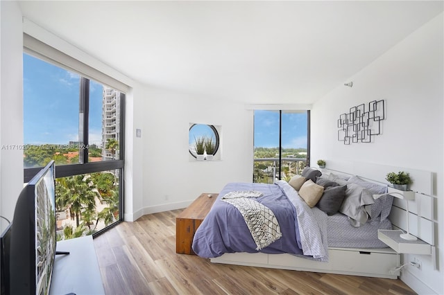 bedroom with multiple windows, floor to ceiling windows, and light wood-type flooring