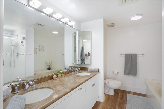 bathroom featuring a washtub, vanity, hardwood / wood-style flooring, and toilet