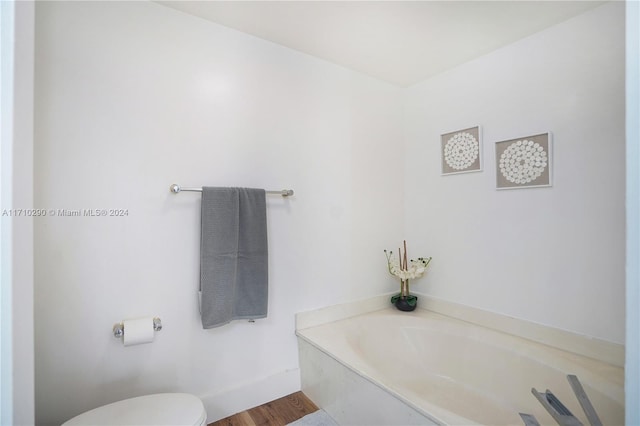 bathroom featuring a tub to relax in, hardwood / wood-style floors, and toilet