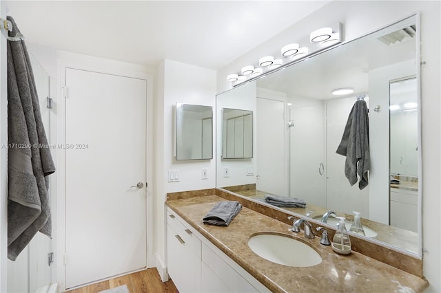 bathroom featuring hardwood / wood-style floors, vanity, and walk in shower