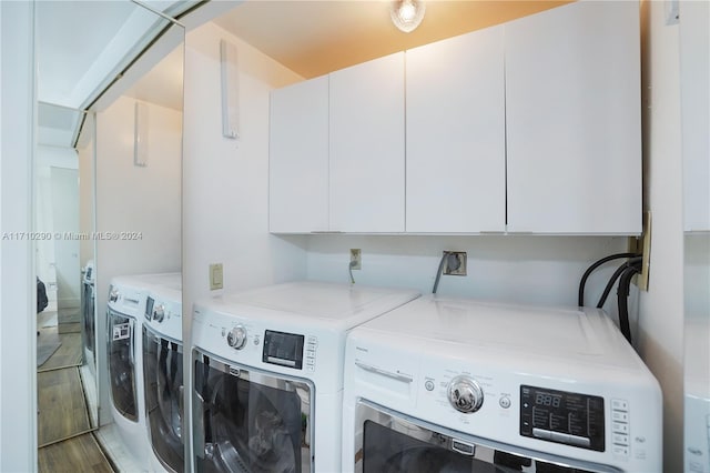 washroom with washing machine and clothes dryer, cabinets, and hardwood / wood-style flooring