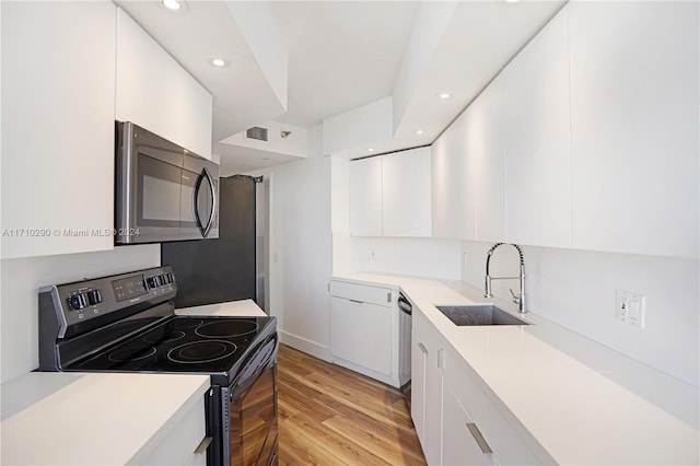 kitchen with white cabinets, black electric range oven, light hardwood / wood-style floors, and sink