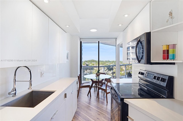 kitchen featuring white cabinetry, sink, black range oven, and light hardwood / wood-style flooring