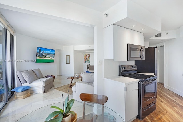 kitchen with electric range, light hardwood / wood-style floors, and white cabinetry