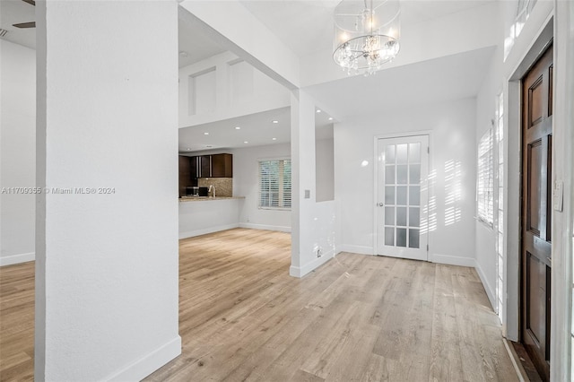 foyer entrance featuring a notable chandelier, plenty of natural light, and light wood-type flooring