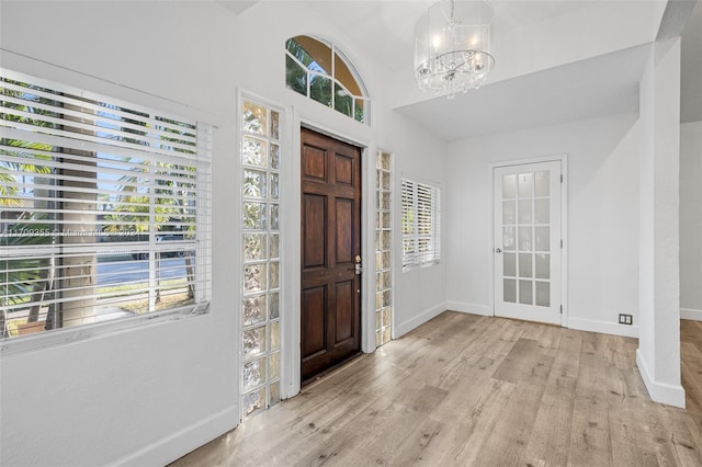 foyer with plenty of natural light, a chandelier, and light hardwood / wood-style flooring