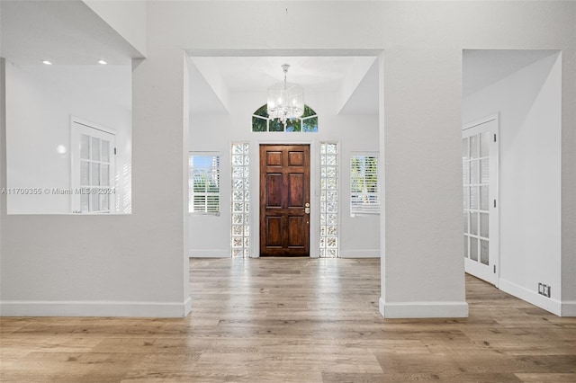 entrance foyer featuring light hardwood / wood-style flooring, a chandelier, and vaulted ceiling