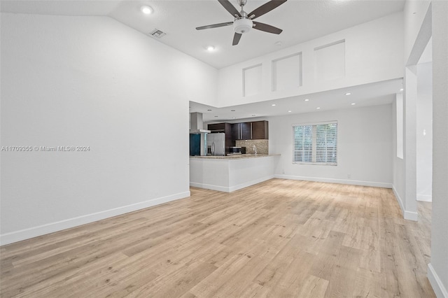 unfurnished living room with ceiling fan, light hardwood / wood-style floors, and high vaulted ceiling