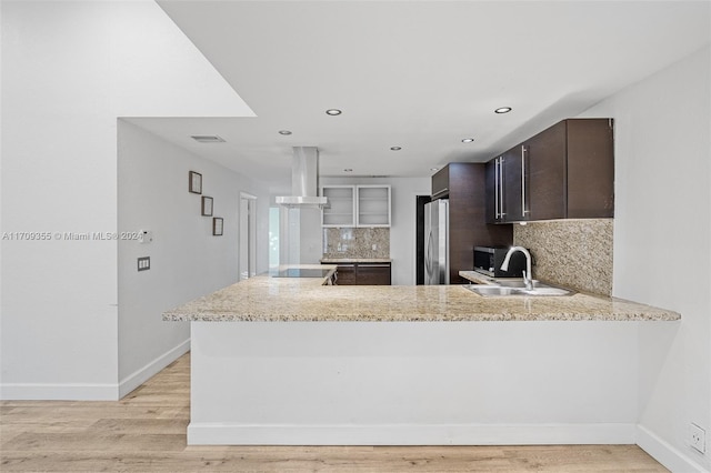 kitchen featuring kitchen peninsula, ventilation hood, stainless steel appliances, and dark brown cabinets