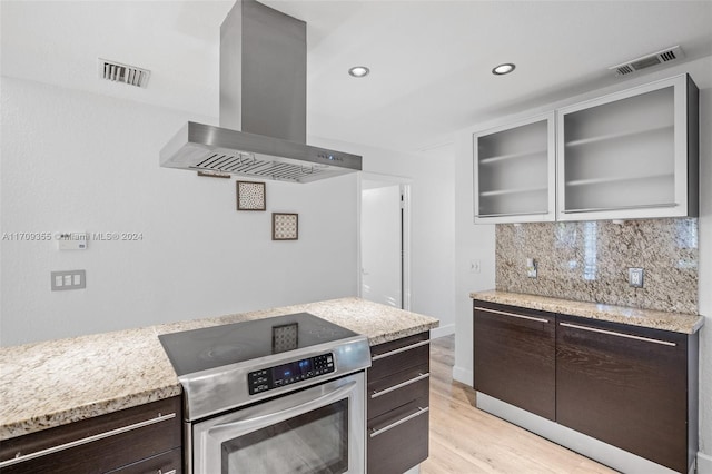 kitchen featuring light hardwood / wood-style flooring, stainless steel stove, exhaust hood, and dark brown cabinets