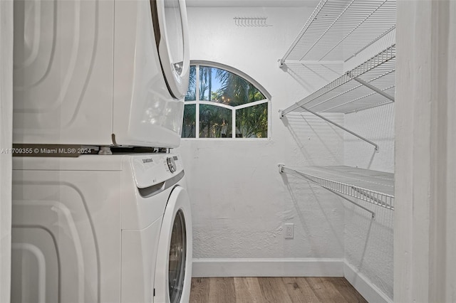 clothes washing area featuring wood-type flooring and stacked washing maching and dryer