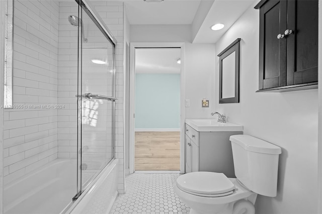 full bathroom with toilet, hardwood / wood-style floors, vanity, and combined bath / shower with glass door