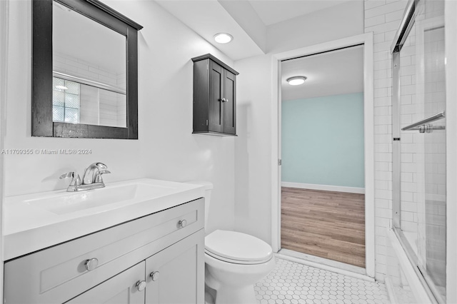 full bathroom with combined bath / shower with glass door, vanity, hardwood / wood-style flooring, and toilet