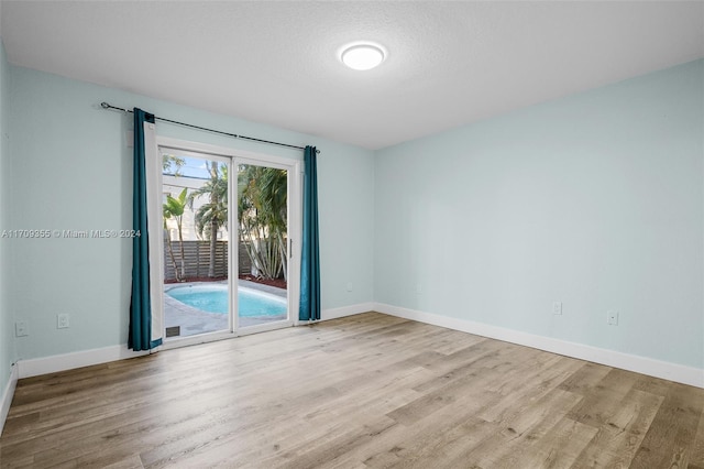 empty room with light hardwood / wood-style flooring and a textured ceiling