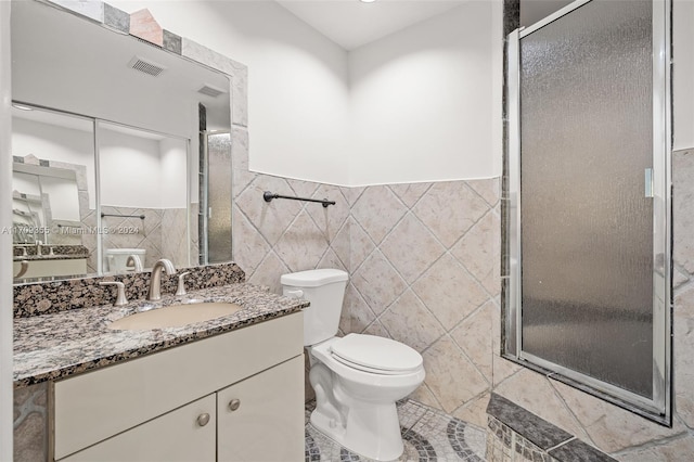 bathroom featuring an enclosed shower, vanity, tile walls, tile patterned flooring, and toilet