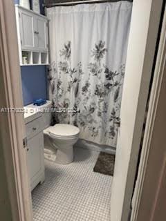 bathroom featuring shower / bath combo with shower curtain, tile patterned flooring, and toilet