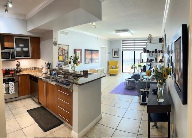 kitchen featuring a peninsula, ornamental molding, stainless steel appliances, and light tile patterned flooring