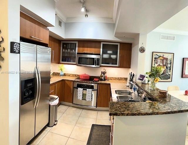 kitchen with stainless steel appliances, visible vents, ornamental molding, a sink, and a peninsula