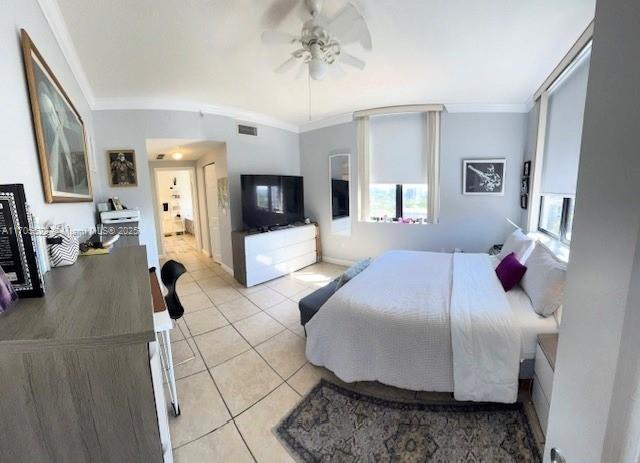 bedroom with a ceiling fan, light tile patterned flooring, visible vents, and crown molding