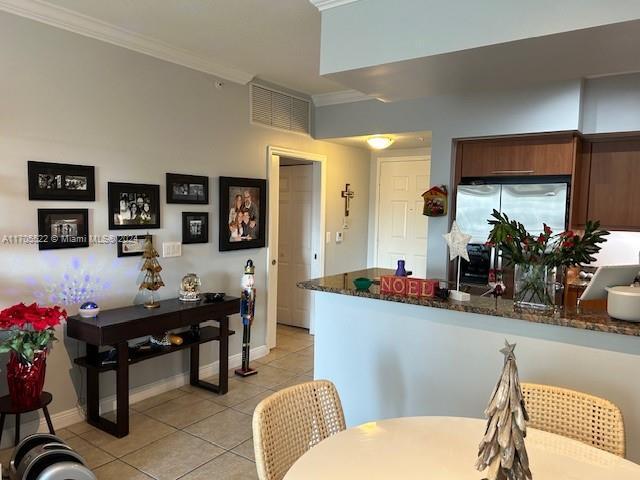 kitchen with crown molding, light tile patterned floors, freestanding refrigerator, a peninsula, and baseboards