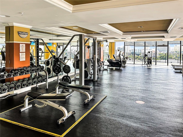 exercise room with a wall of windows, a raised ceiling, visible vents, and crown molding