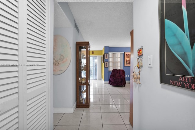 hallway featuring light tile patterned flooring and a textured ceiling