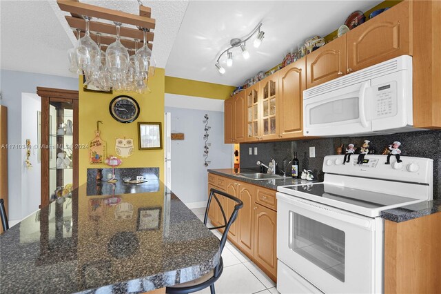 kitchen with tasteful backsplash, a textured ceiling, white appliances, sink, and light tile patterned flooring