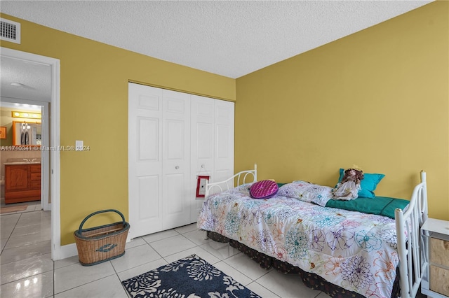 tiled bedroom with a closet and a textured ceiling