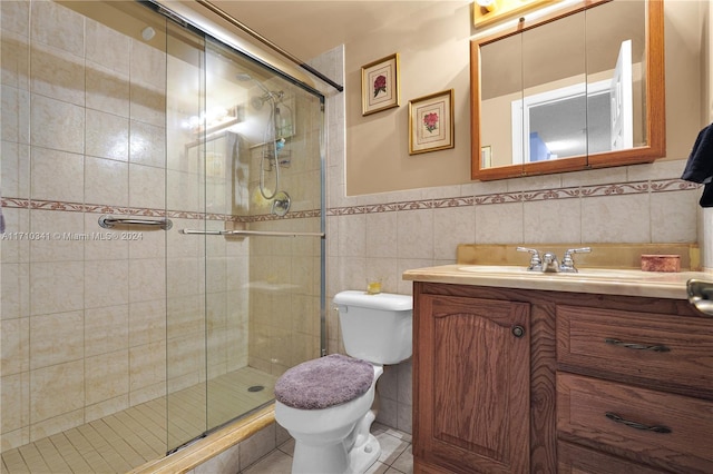 bathroom with a shower with door, vanity, tile walls, and toilet