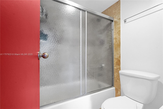 bathroom featuring enclosed tub / shower combo and toilet