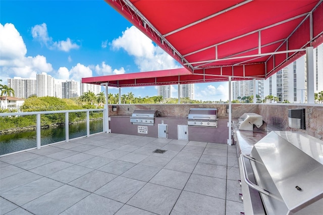 view of patio / terrace featuring a grill, a water view, and exterior kitchen