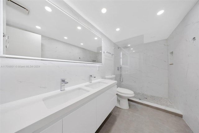 bathroom featuring tiled shower, vanity, toilet, and tile walls