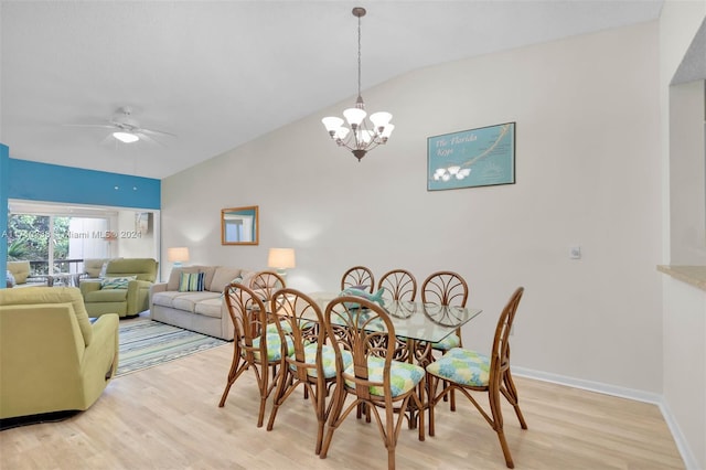 dining space with ceiling fan with notable chandelier, light wood-type flooring, and vaulted ceiling