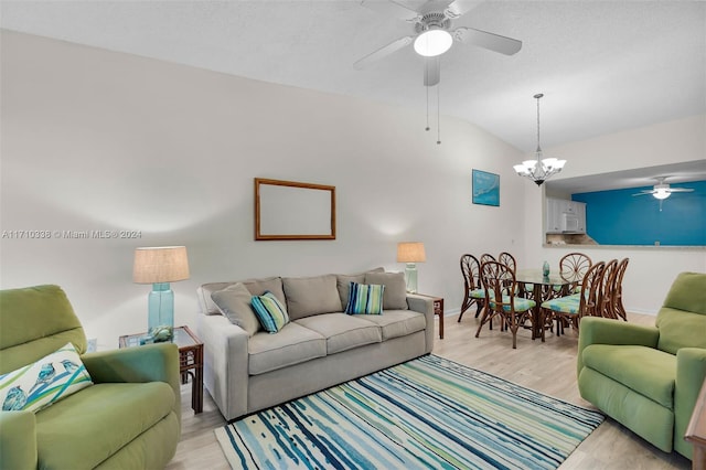 living room featuring a notable chandelier, lofted ceiling, and light hardwood / wood-style flooring