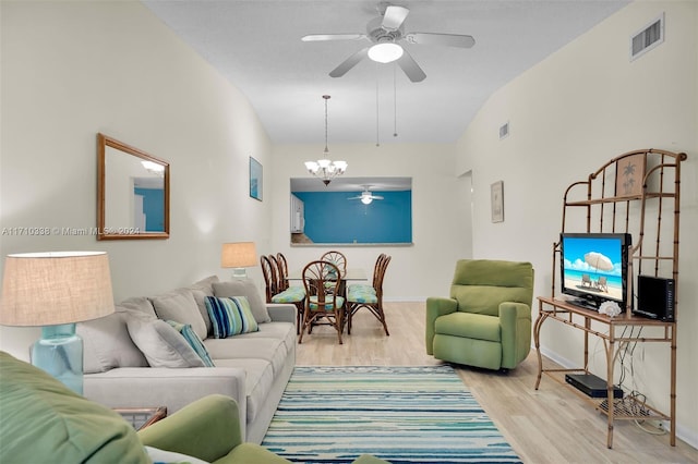 living room featuring ceiling fan with notable chandelier, light hardwood / wood-style floors, and vaulted ceiling