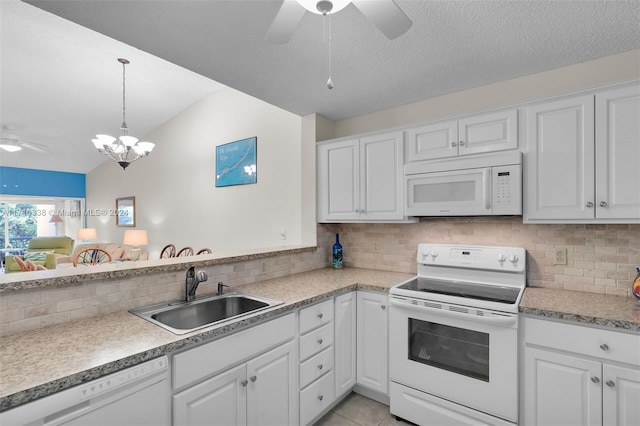 kitchen with backsplash, white appliances, sink, white cabinets, and lofted ceiling