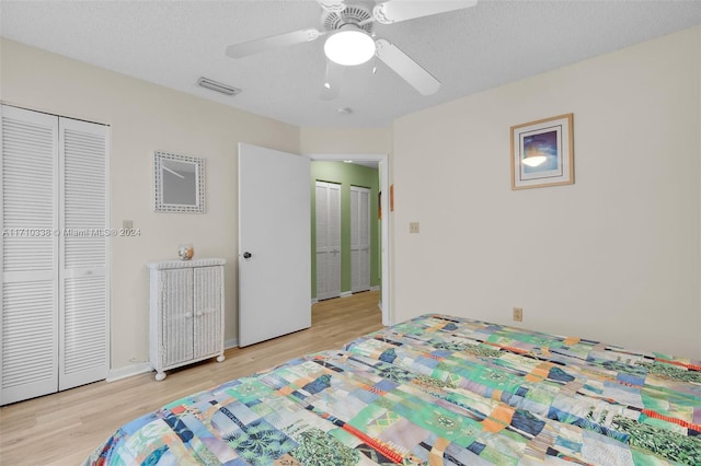 bedroom with ceiling fan, light wood-type flooring, and a textured ceiling