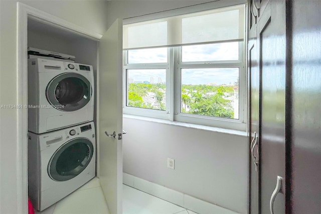 washroom with elevator, tile patterned floors, and stacked washer and clothes dryer