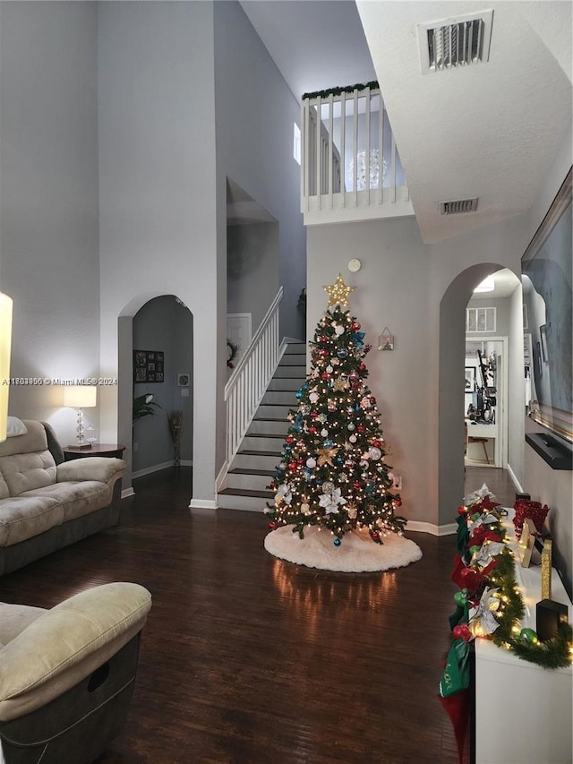 living room featuring dark hardwood / wood-style flooring and a towering ceiling