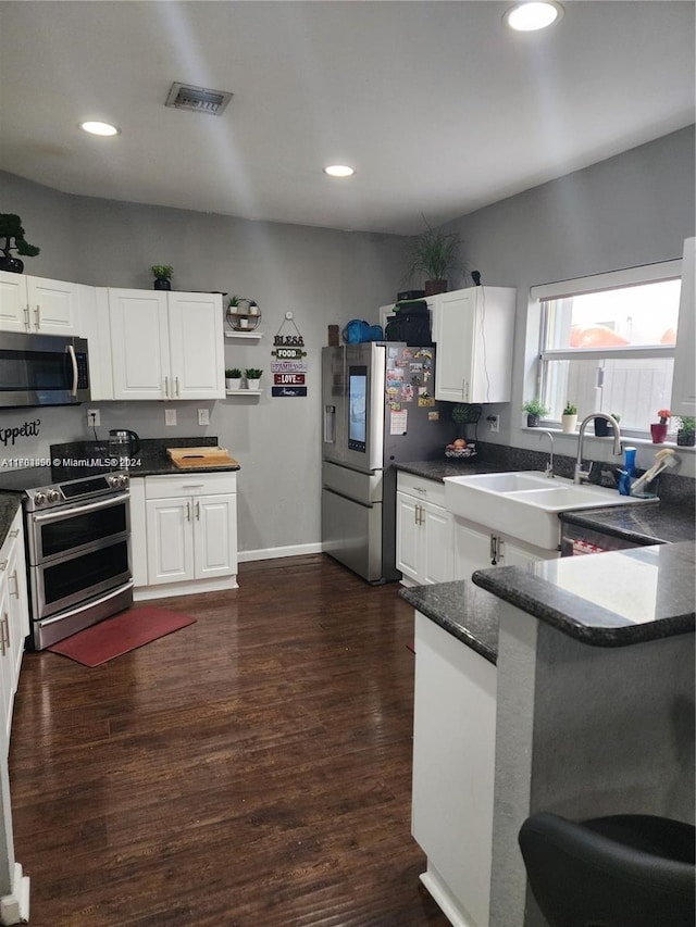 kitchen with dark hardwood / wood-style floors, white cabinetry, sink, and appliances with stainless steel finishes